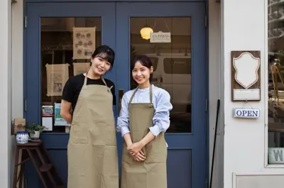 Two female business owners standing outside the front doors of their store.
