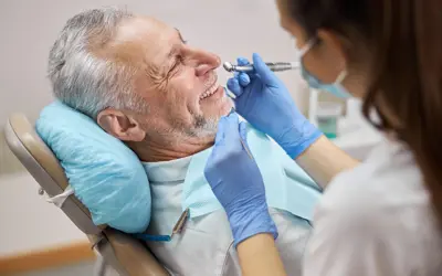 Dental hygienist using a drill during a dental treatment on an older man