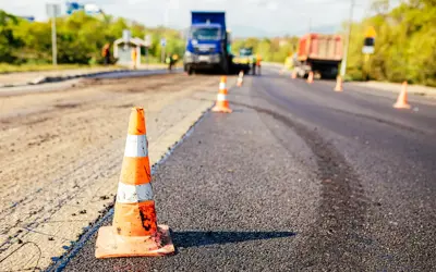  Traffic cones on road with a large layer of fresh hot asphalt for road construction.