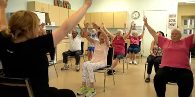 Instructor guiding seniors through a seated exercise class