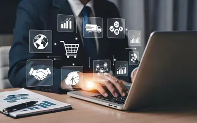 Business person working on a computer with icons representing supplies and purchasing
