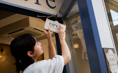 Woman turning an open sign on her storefront