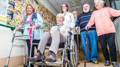 Group of older adults using various mobility devices to walk.