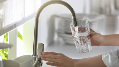 Close up of two hands filling a glass with tap water.